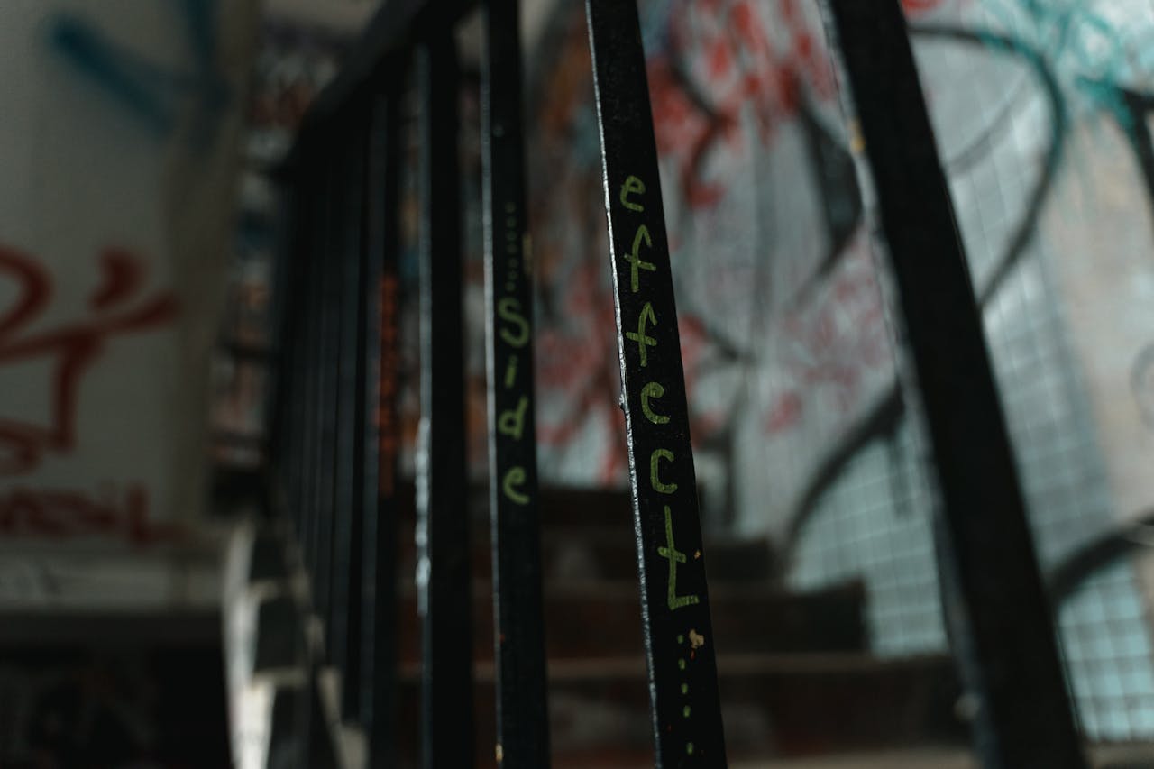 Graffiti-covered staircase railing with the words side effect in an urban building.