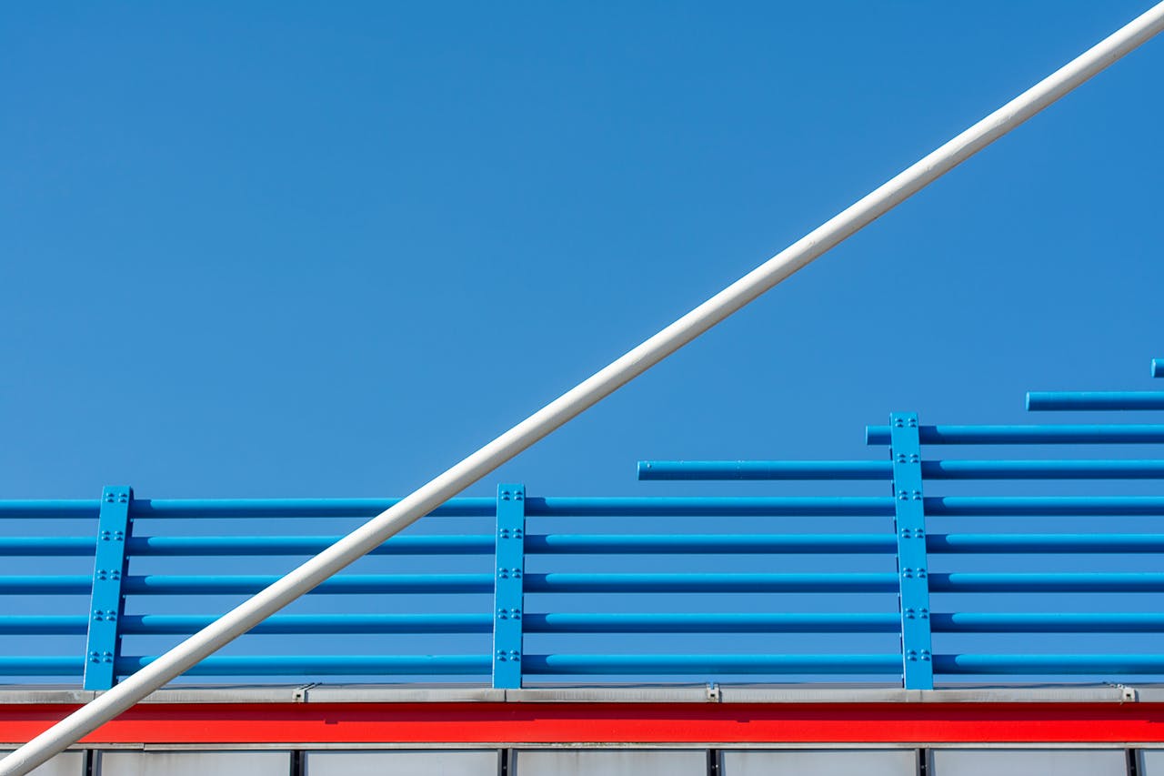 Minimalist architectural structure featuring blue and red lines against a clear blue sky.